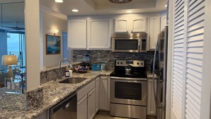 A modern kitchen with granite countertops, stainless steel appliances, and a view to the outside.