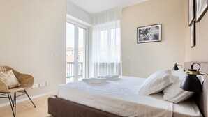 Ein Hotelzimmer mit Bett, Stuhl, Lampe und einem Fenster mit Vorhängen.