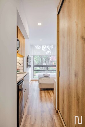 Eine moderne Küche mit Holzausstattung, einem Einbauofen und einem Fenster mit Blick auf einen Balkon.