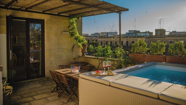 Un espace piscine aménagé sur le toit, avec une pergola, des sièges et une vue sur le paysage urbain.