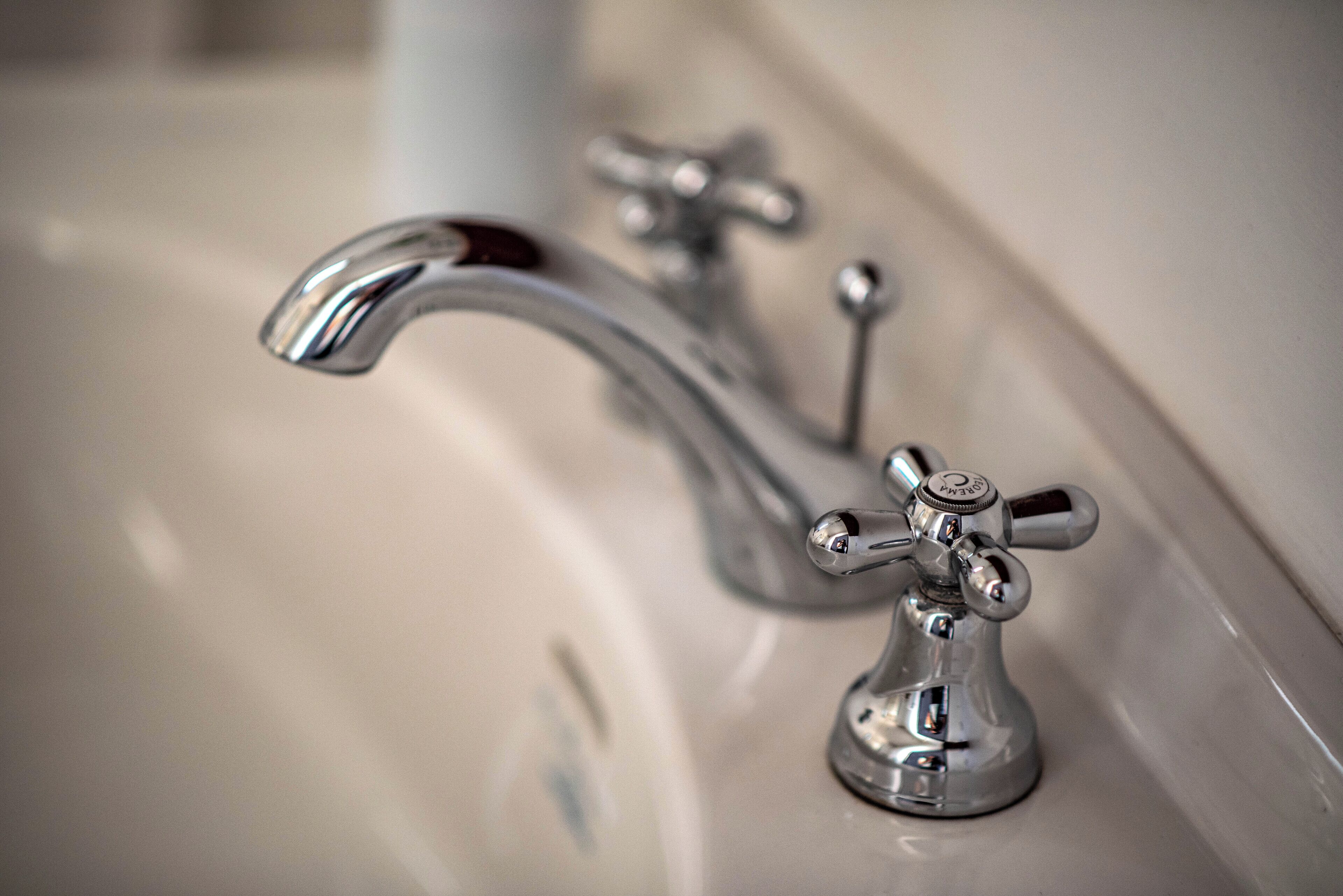 A bathroom sink with two chrome faucets.