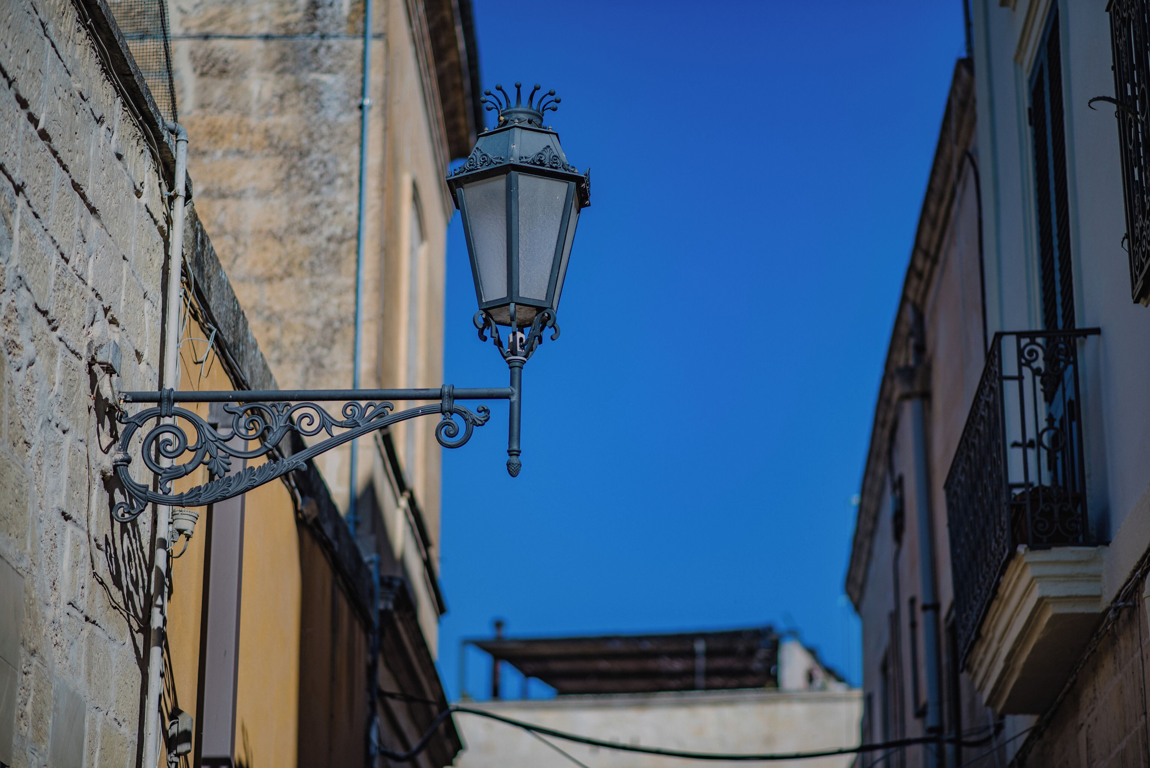 A street lamp attached to a building with ornate metalwork.