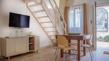 Ein Essbereich mit Holztisch und Stühlen, einem an der Wand befestigten Fernseher und einer Treppe zu einer anderen Ebene.
