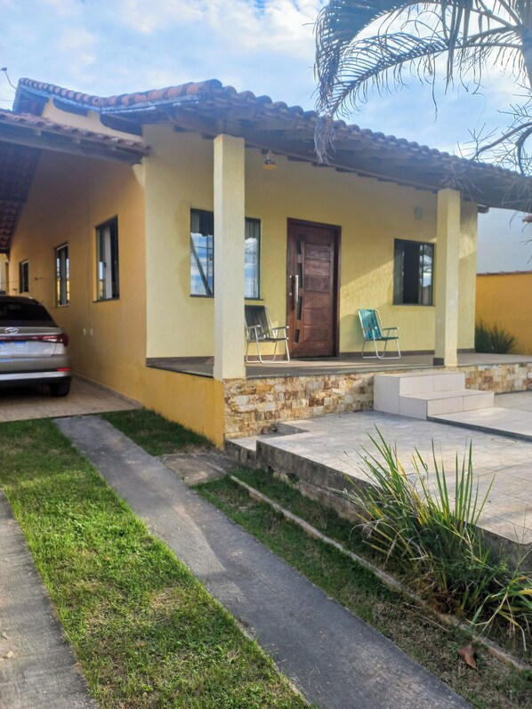 A residential house with a tiled roof, a front porch, and a parked car.