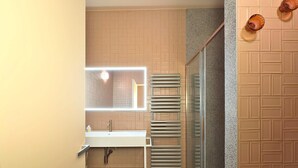 Baño con espejo, lavabo, toallero y zona de ducha.