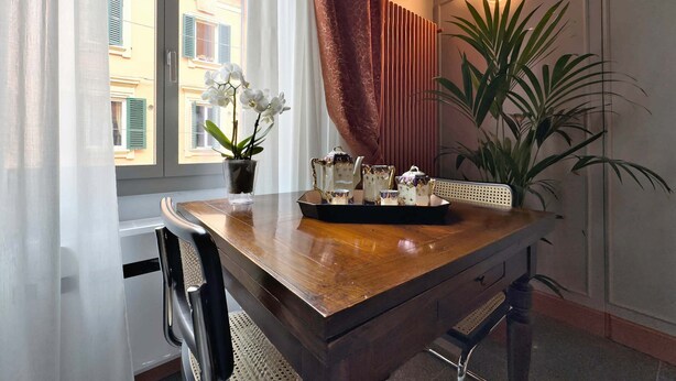 A wooden desk with a vase of white flowers, a tray with teacups, and a potted plant. - Cinisca Suite Blue in Bologna (Bologna)