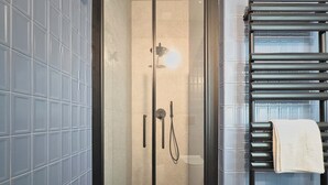 A modern bathroom with a glass-enclosed shower, tiled walls, and a black towel rack. - Cinisca Suite Blue in Bologna (Bologna)