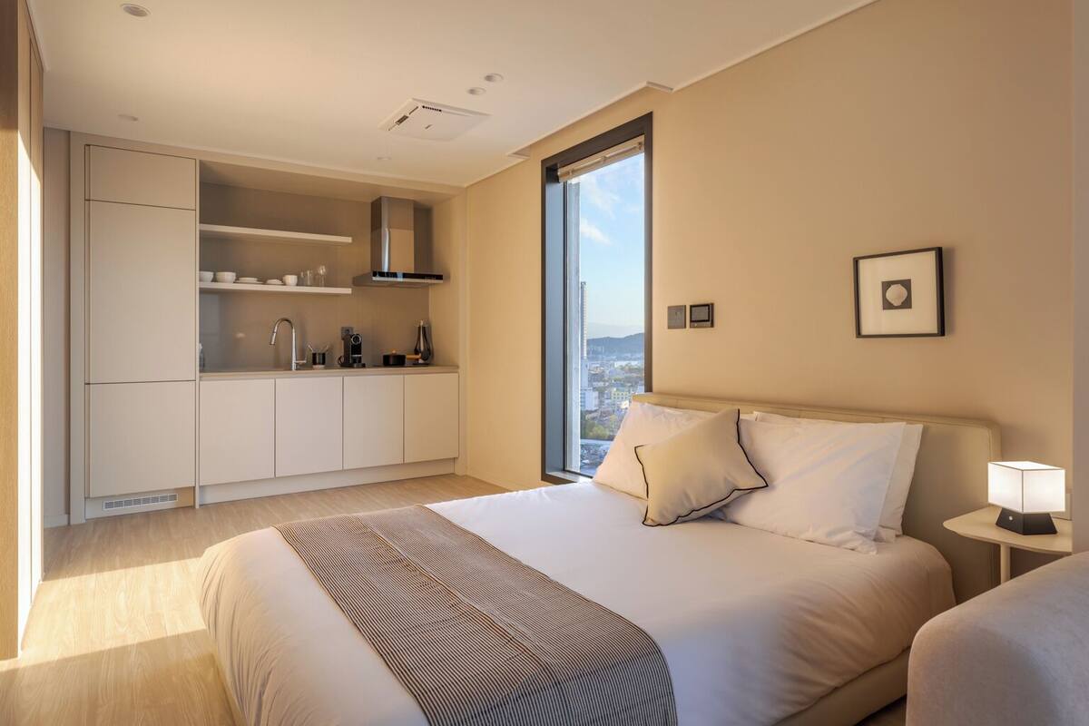 Une chambre d’hôtel moderne avec un grand lit, une petite kitchenette et une vue sur la ville.