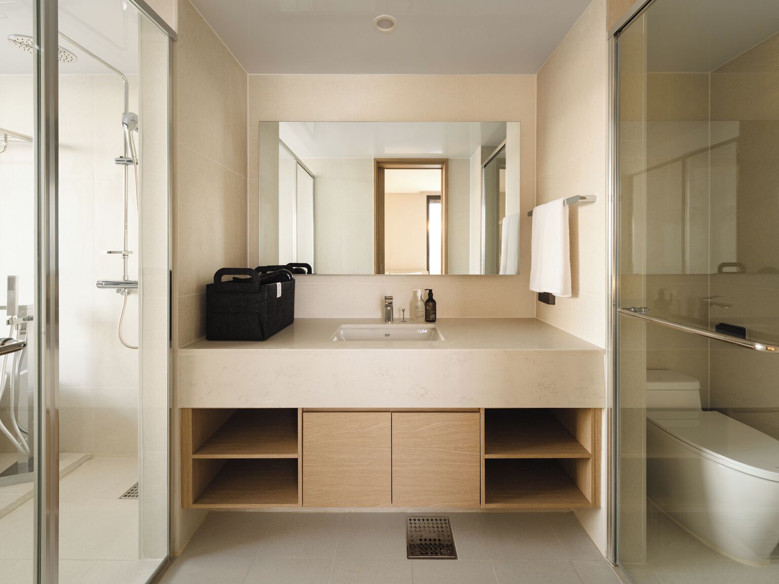 A modern bathroom with a large mirror, a sink, and a shower area.