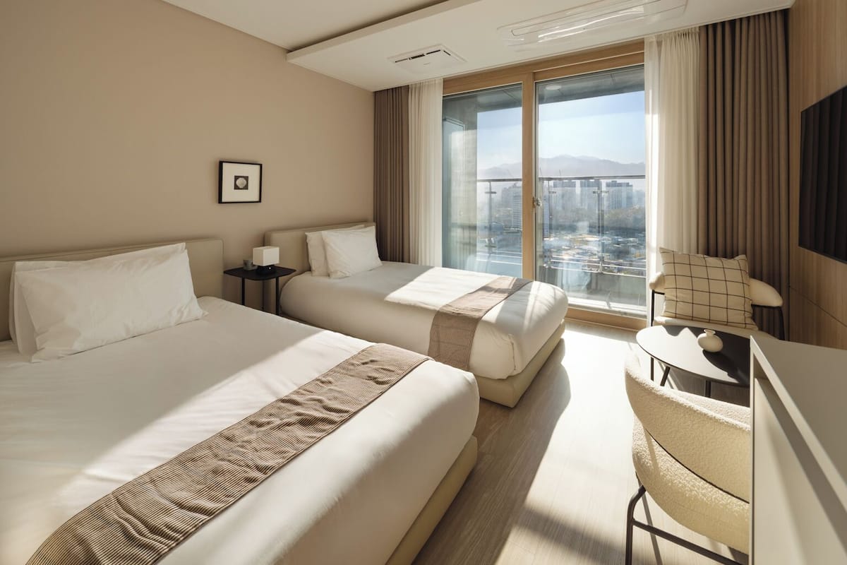 Une chambre d’hôtel avec deux lits, un bureau et une chaise.