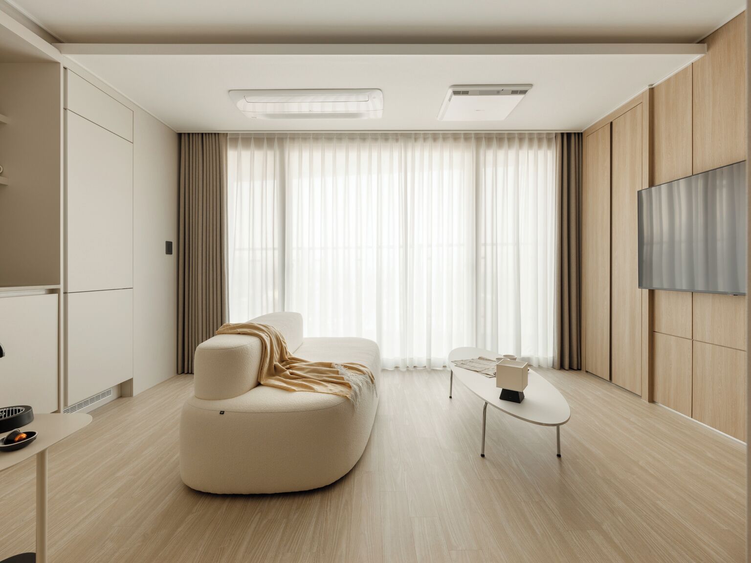 A modern living room with a curved sofa, a small table, and a TV mounted on the wall.