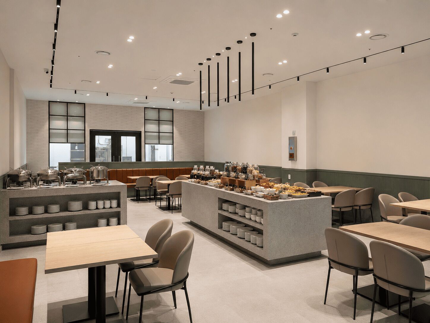 Un café moderno con una isla central, zona de estar y vistas de la ciudad.