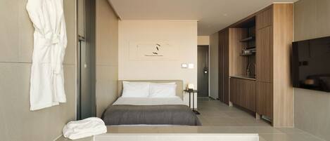 A modern hotel room with a large bed, a glass-enclosed jacuzzi, a wooden wardrobe, and a flat-screen TV mounted on the wall.