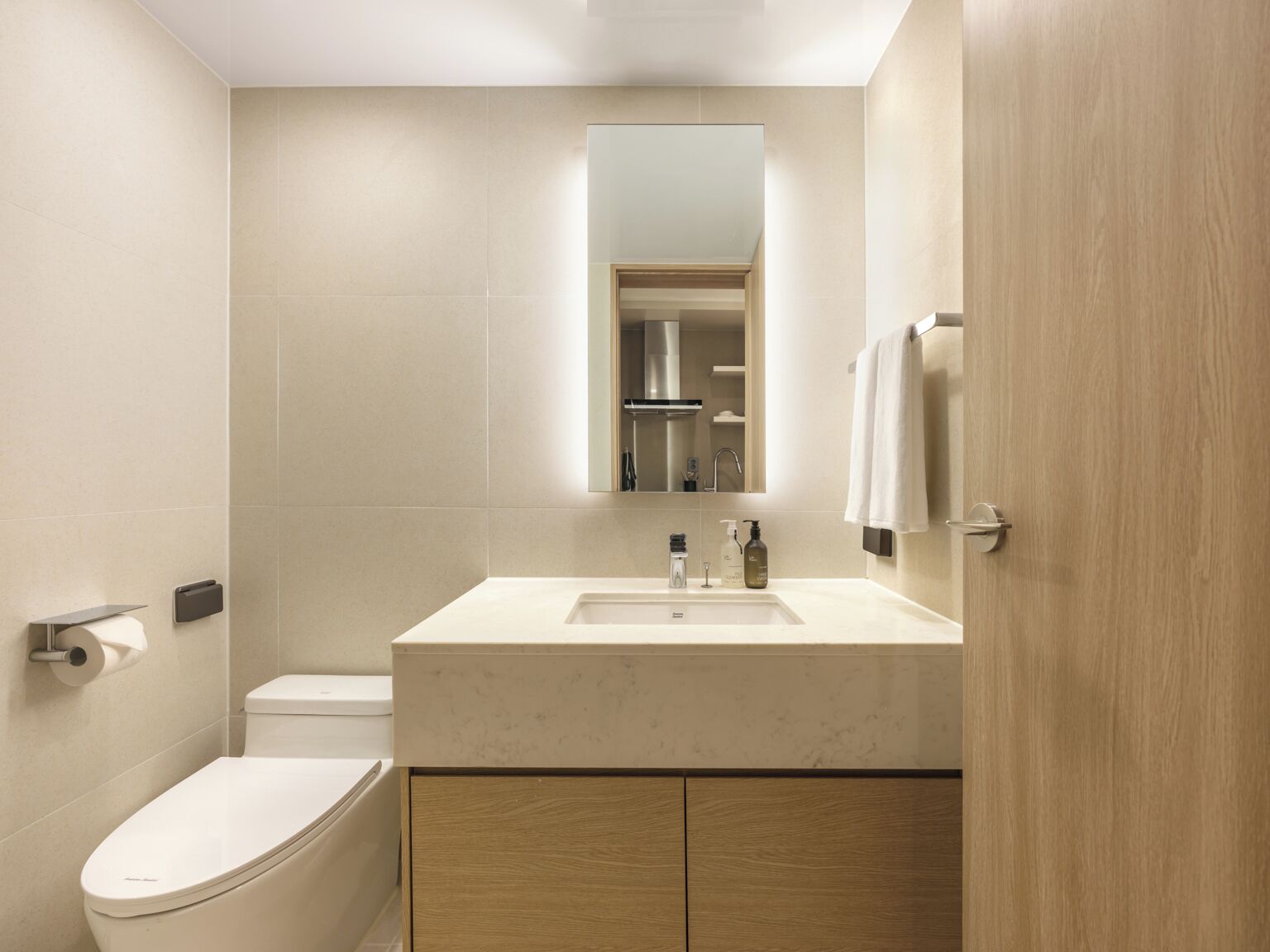 A modern bathroom with a toilet, sink, and mirror.