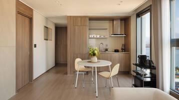 A modern, well-lit room with a dining area, a sofa, and a kitchen area with a view.