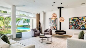 Amplia sala de estar con un ventanal grande, vista a la piscina y muebles modernos.