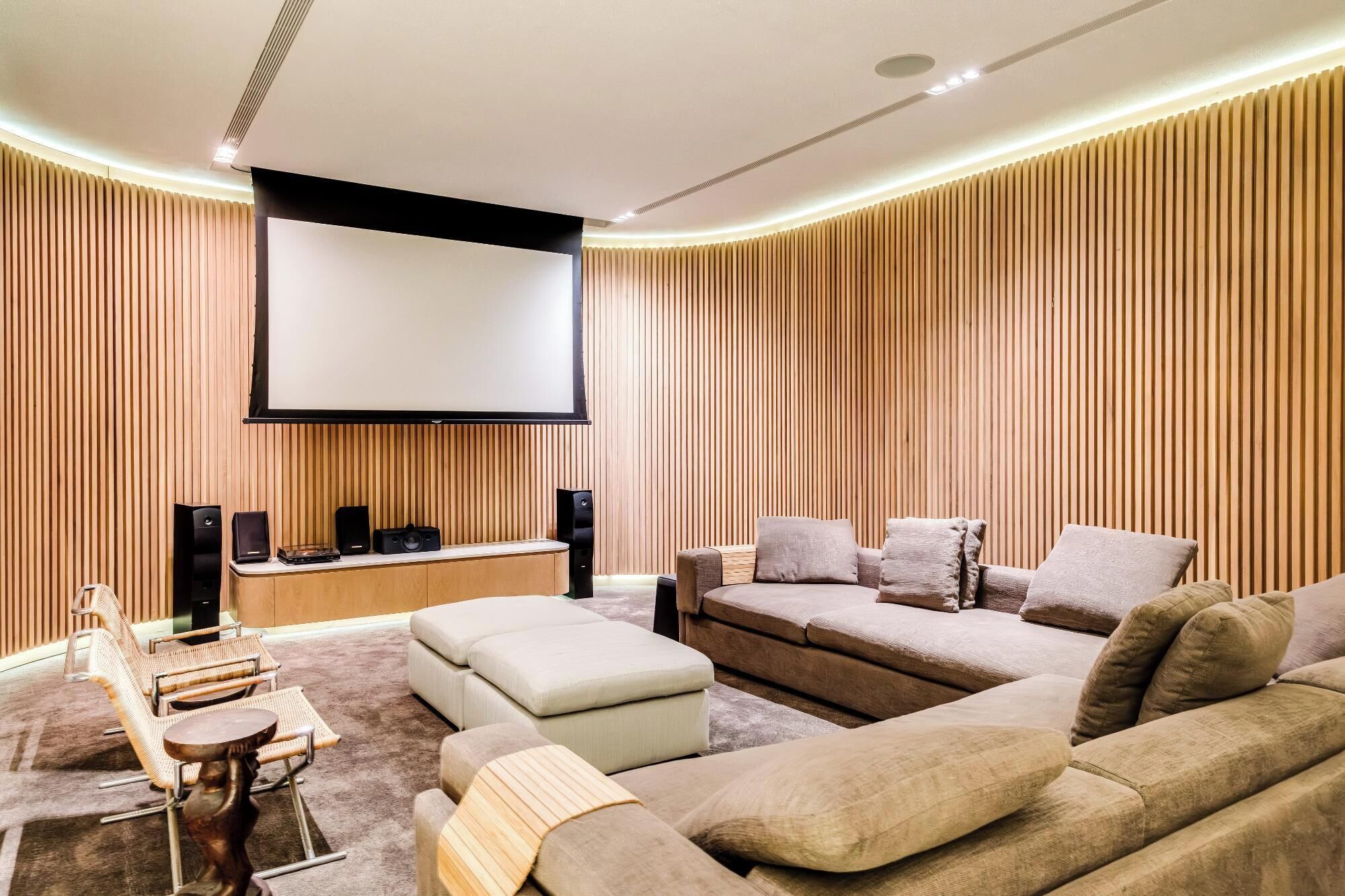 A modern living room with a large flat-screen TV, a sofa, a coffee table, and a side table with speakers.