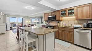A modern kitchen with granite countertops, wooden cabinets, a built-in microwave, and a stainless steel dishwasher. - 510 - Cozy 1 bedroom Fantastic View (New Smyrna Beach)