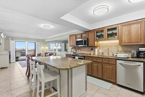 A modern kitchen with granite countertops, wooden cabinets, a built-in microwave, and a stainless steel dishwasher. - 510 - Cozy 1 bedroom Fantastic View (New Smyrna Beach)