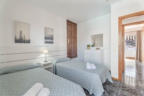 A hotel room with two beds, a wooden door, a small bedside table with a lamp, a dresser, and a mirror. - Vacation Apartment "Golden Sun Penthouse" with Shared Pool, Private Terrace & Wi-Fi (Playa de las Américas)