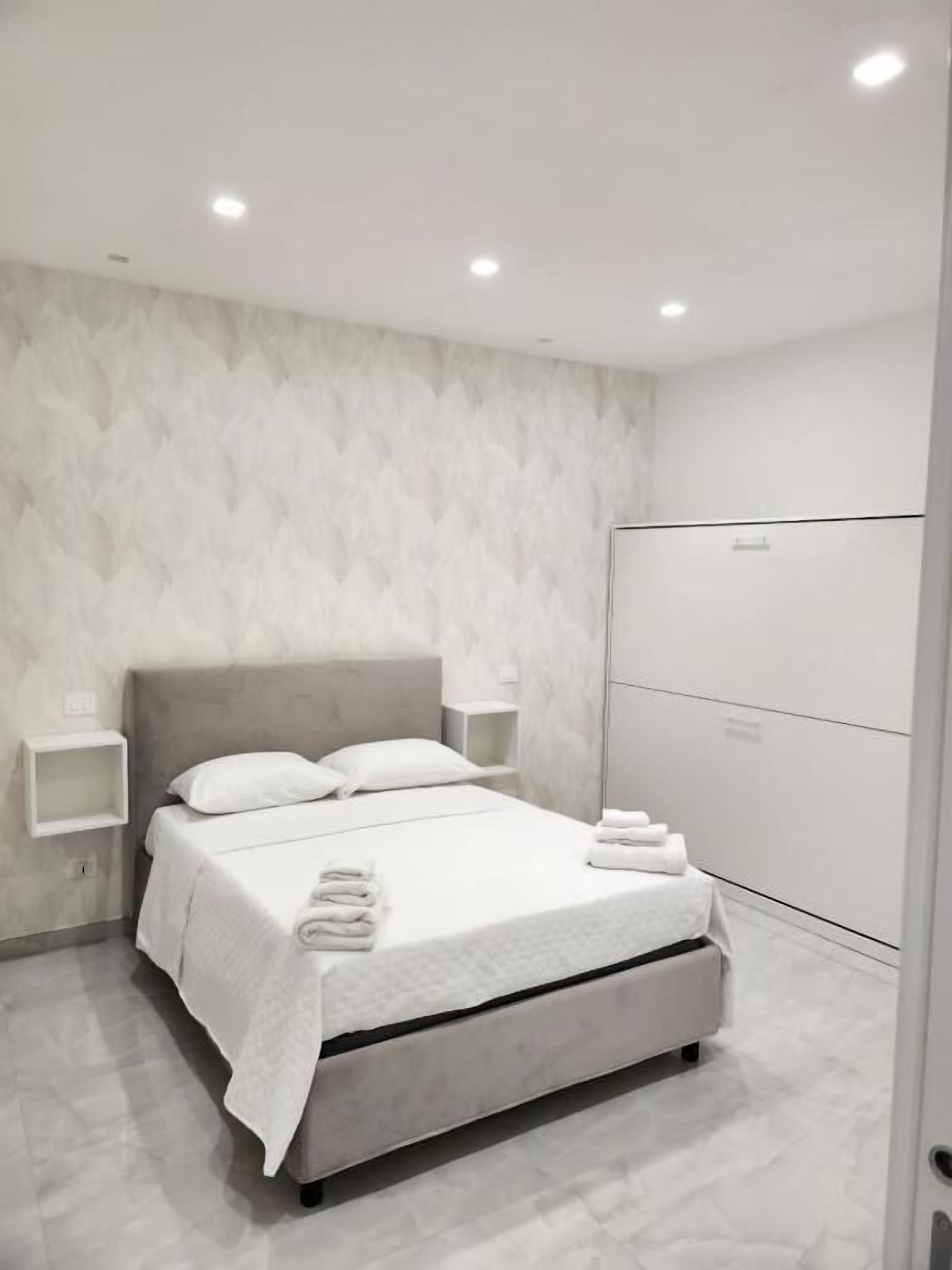 A modern bedroom with a bed, bedside tables, and a wardrobe.