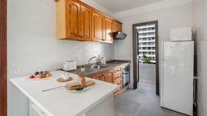 A modern kitchen with wooden cabinets, a white countertop, a sink, and a refrigerator. - Ocean Breeze Penthouse Apartment with Shared Pool, Private Terrace and Wi-Fi (Playa de las Américas)