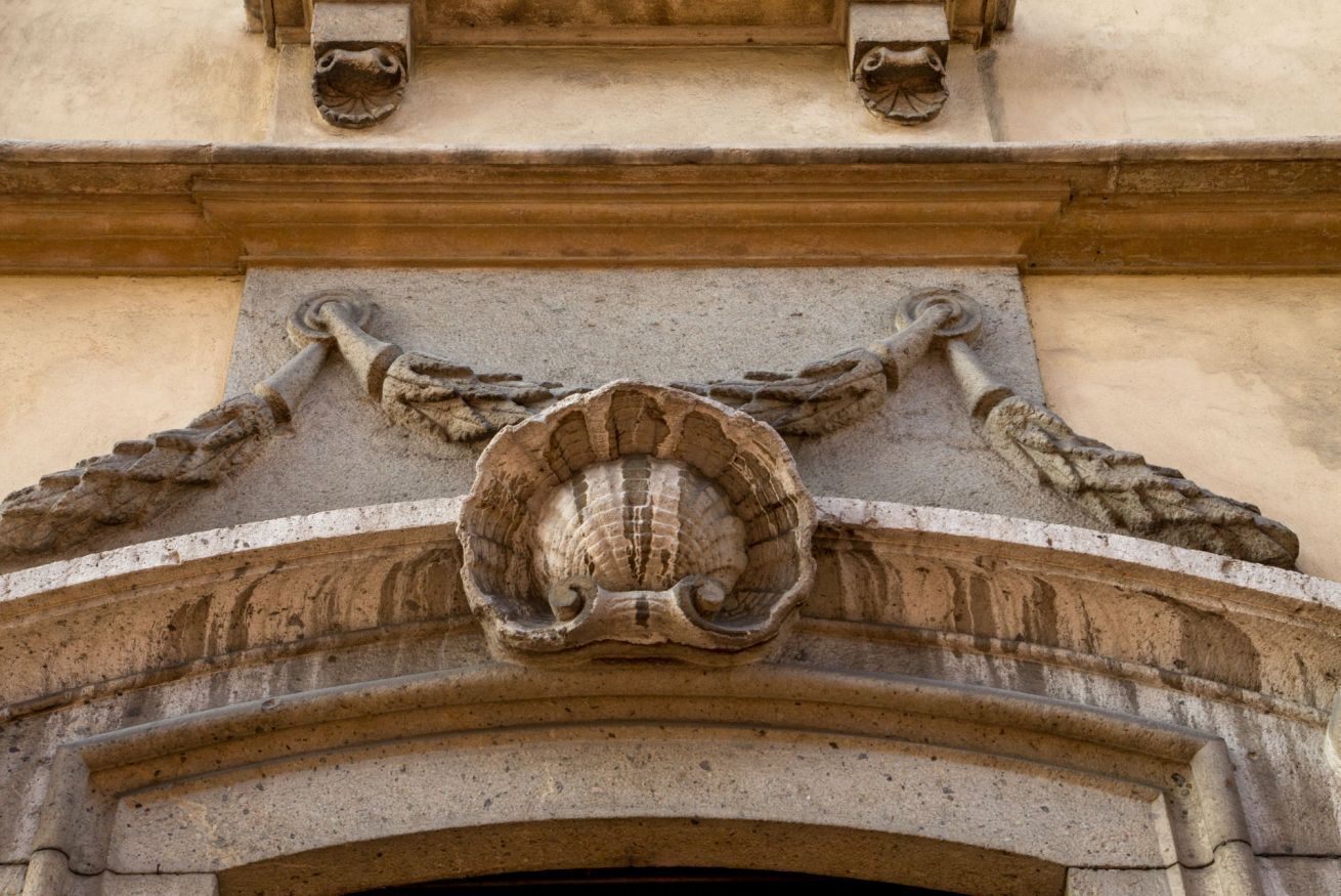 A stone architectural detail with a shell-like design and two wing-like structures.