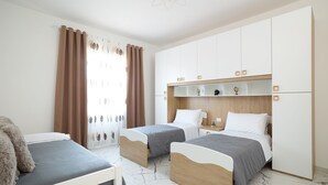 Een slaapkamer met twee bedden, een houten garderobe en een wit plafond.