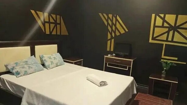 A hotel room with a bed, bedside tables, a dresser, and decorative wall art. - Üsküdar Hotel Batum (Batumi)