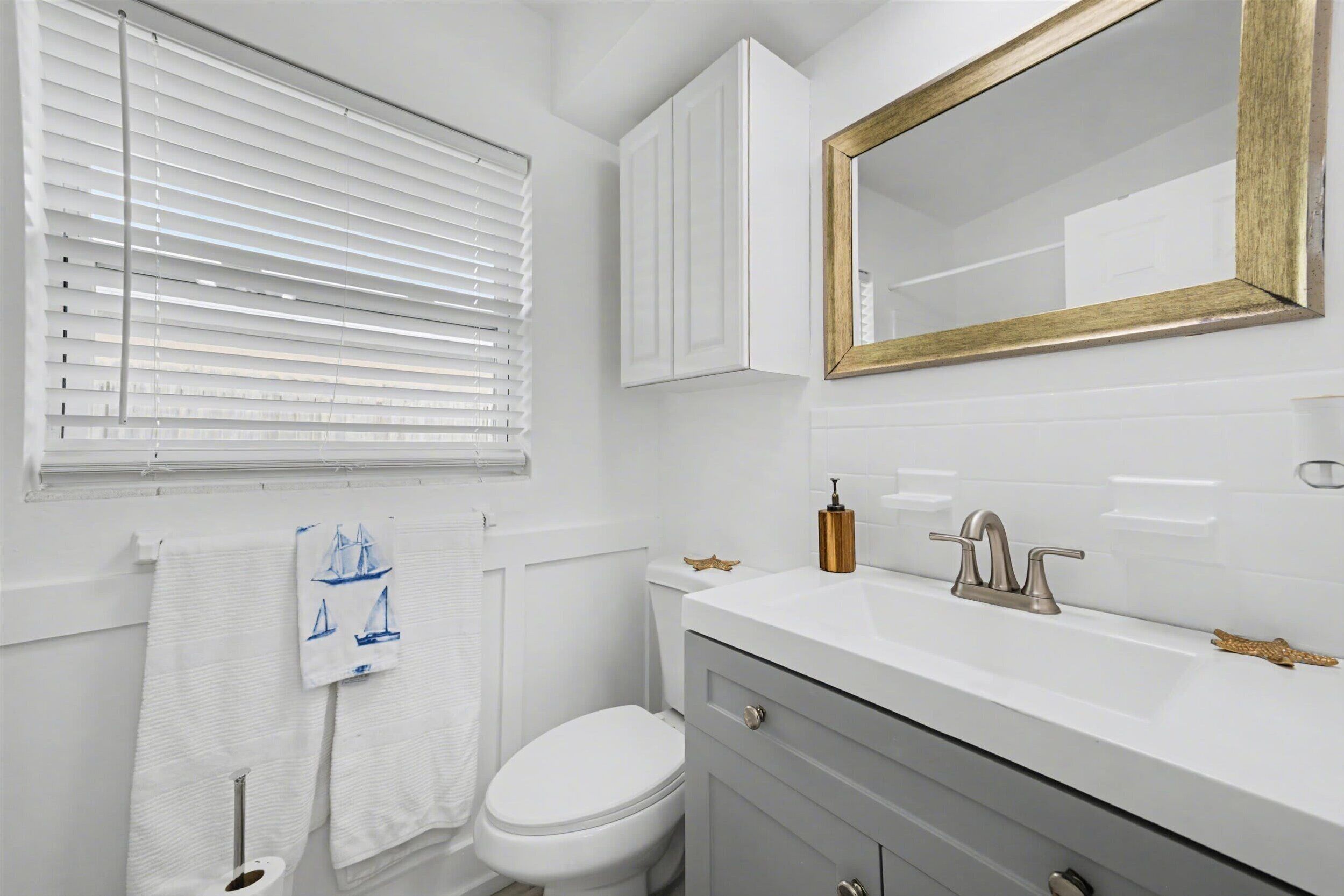 Un baño con un inodoro blanco, un lavabo con grifo dorado y un espejo con marco dorado.