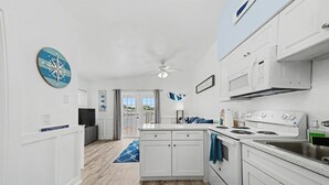 A modern kitchen with white cabinetry, a stove, microwave, and a ceiling fan. - Waterway Vista Suite Pet Friendly Boat Dock (Indian Rocks Beach)