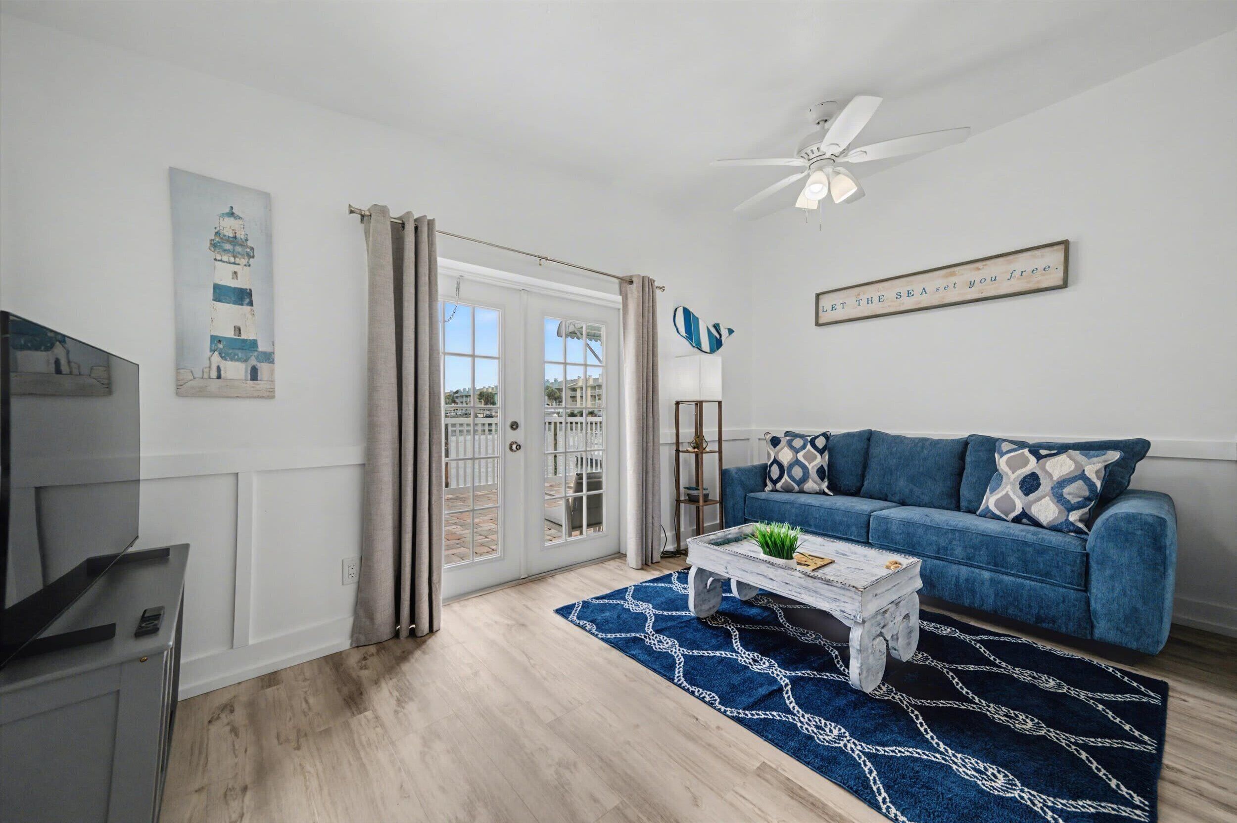 A living room with a blue sofa, a coffee table, and a painting of a lighthouse.