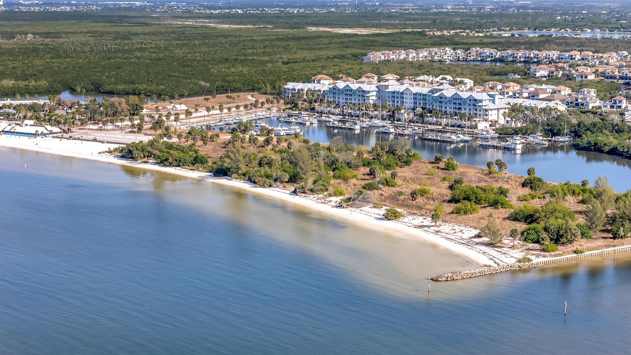 A coastal resort with multiple buildings, a marina, and a beach.