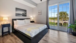 A modern bedroom with a large bed, two bedside lamps, a ceiling fan, and a view of the outdoors through a sliding glass door. - The Mangrove Waterfront Pool Hot Tub Near Beach (Ruskin)