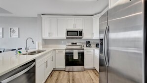 A modern kitchen with white cabinets, stainless steel appliances, and a dishwasher. - The Mangrove Waterfront Pool Hot Tub Near Beach (Ruskin)