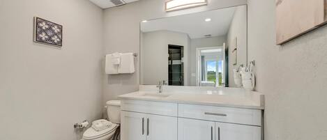 Un baño moderno con lavamanos, tocador y retrete blancos.