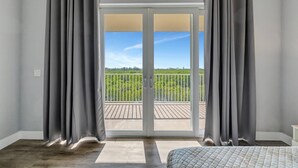 A bedroom with a large sliding glass door leading to a balcony. - The Mangrove Waterfront Pool Hot Tub Near Beach (Ruskin)