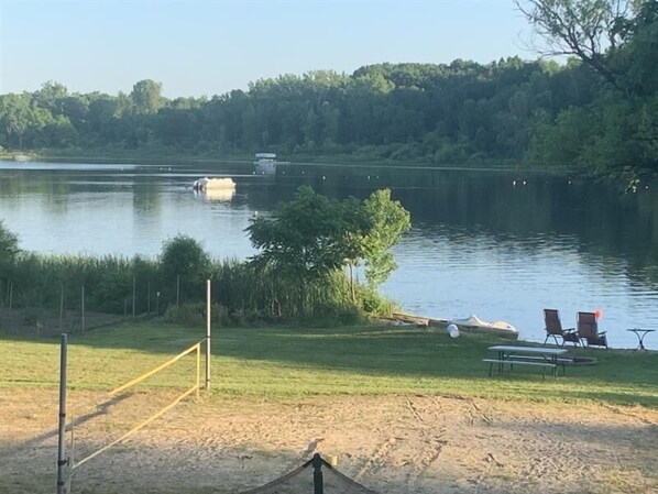 Une vue sur le lac avec un quai pour bateaux, des tables de pique-nique et un filet de volley-ball.