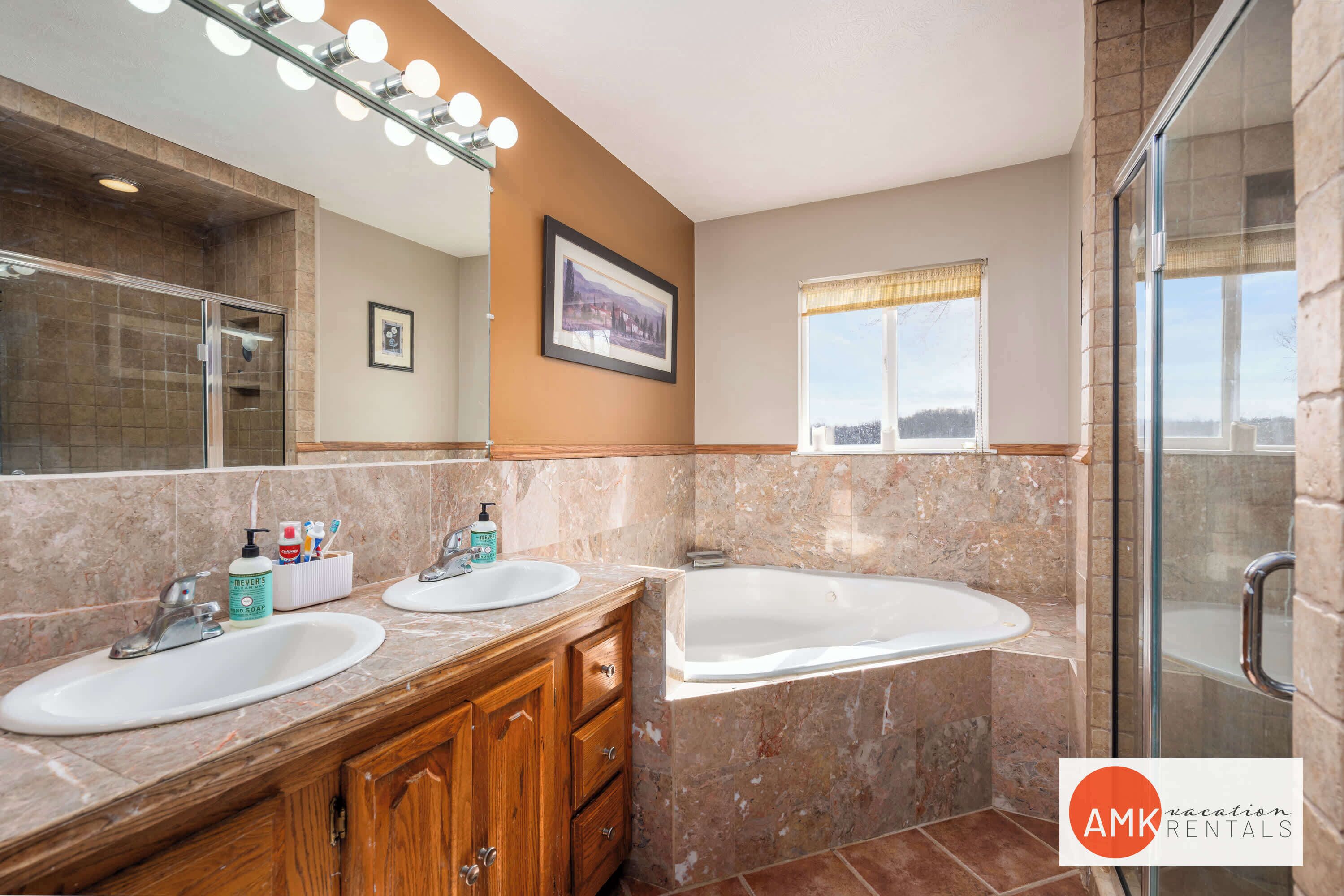 A bathroom with two sinks, a large mirror, and a shower area.