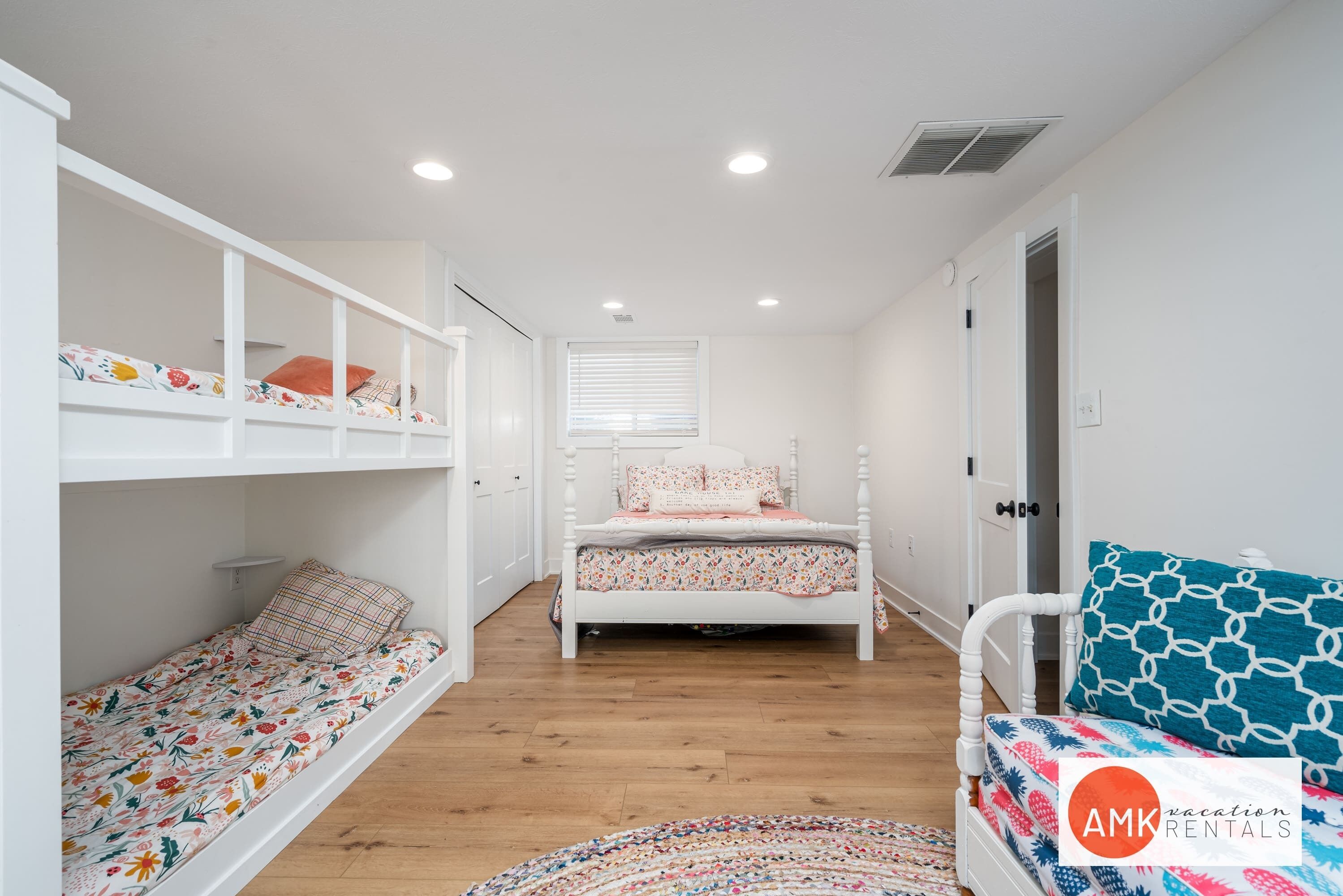 Une chambre avec des lits superposés, un lit simple, une chaise et un tapis à motifs.