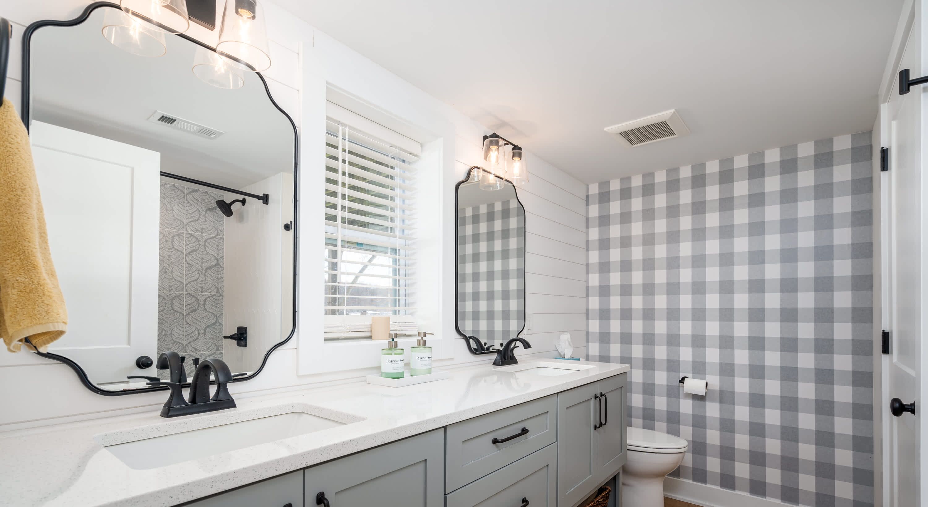 Une salle de bain avec un lavabo blanc, deux miroirs, une douche et des toilettes.