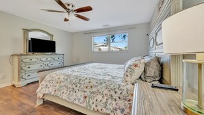 A bedroom with a bed, dresser, ceiling fan, window, and a TV. - Sleeps 8 Pets Welcome Fenced In Backyard (Sarasota)