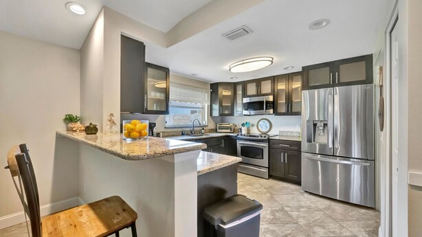 A modern kitchen with granite countertops, stainless steel appliances, and a built-in island with seating. - Sleeps 8 Pets Welcome Fenced In Backyard (Sarasota)