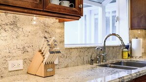 Eine Küche mit Granit Arbeitsplatten, einem Messerblock, einer Spüle und Holzschränken.