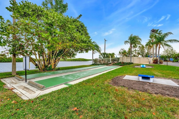A park with a shuffleboard court, trees, and a body of water. - Sunset Suite - Private Balcony Gym Pool (Ruskin)