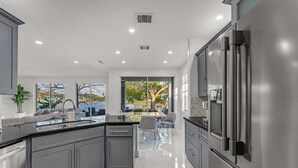 A modern kitchen with a central island, stainless steel appliances, and a view to the outdoors. - Waterview Villa Sleeps 10 BBQ Kayaks Games (Miami)
