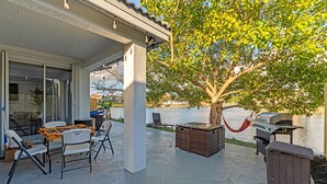 An outdoor patio with a table and chairs, a grill, and a hammock. - Waterview Villa Sleeps 10 BBQ Kayaks Games (Miami)