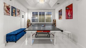 A ping pong table in a room with white walls, a bench, and artwork. - Waterview Villa Sleeps 10 BBQ Kayaks Games (Miami)