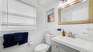 Un baño con inodoro, lavamanos y espejo.