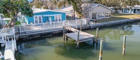 A waterfront property with a dock, a small building with a blue exterior, and a grassy area.